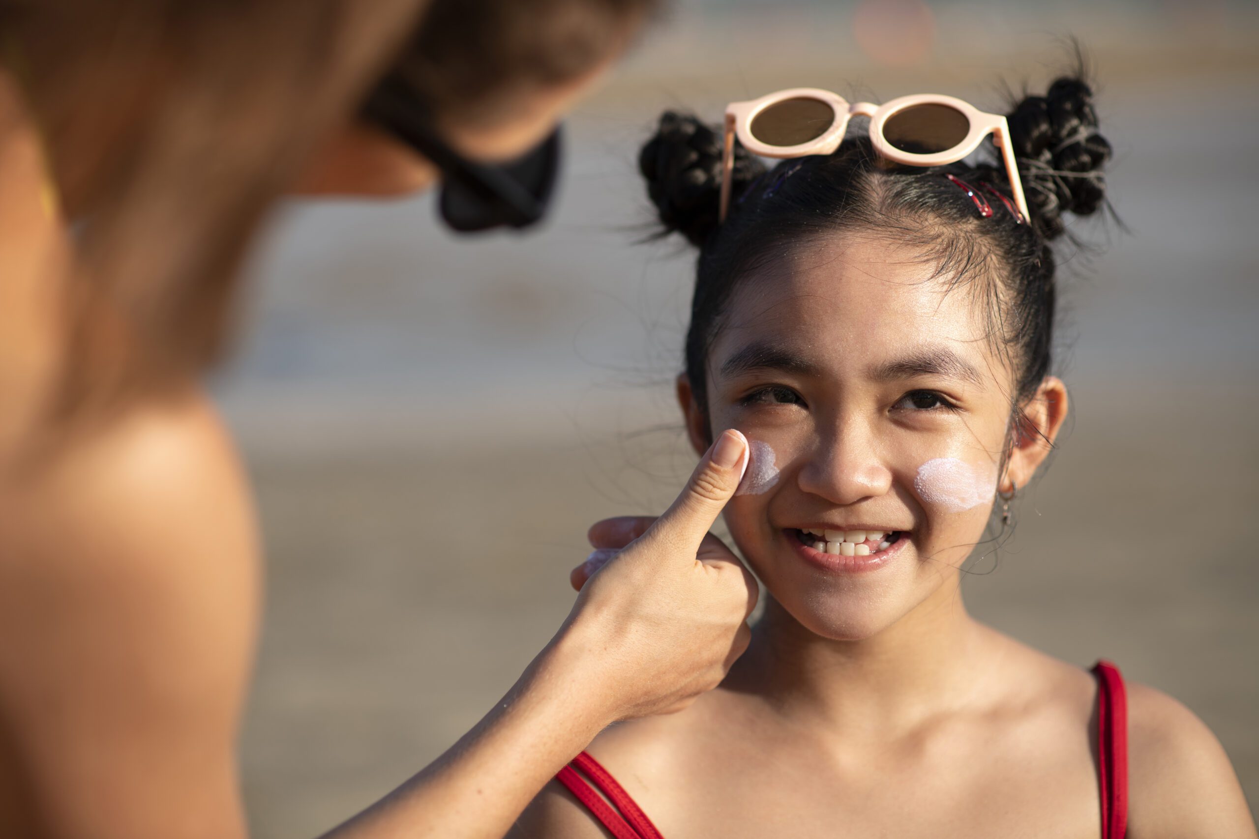 Young girl getting sunscreen on her face