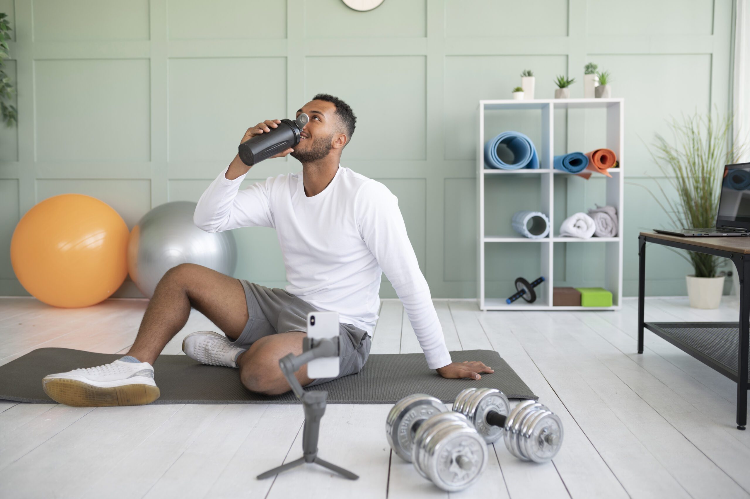 Man exercising at home drinking water