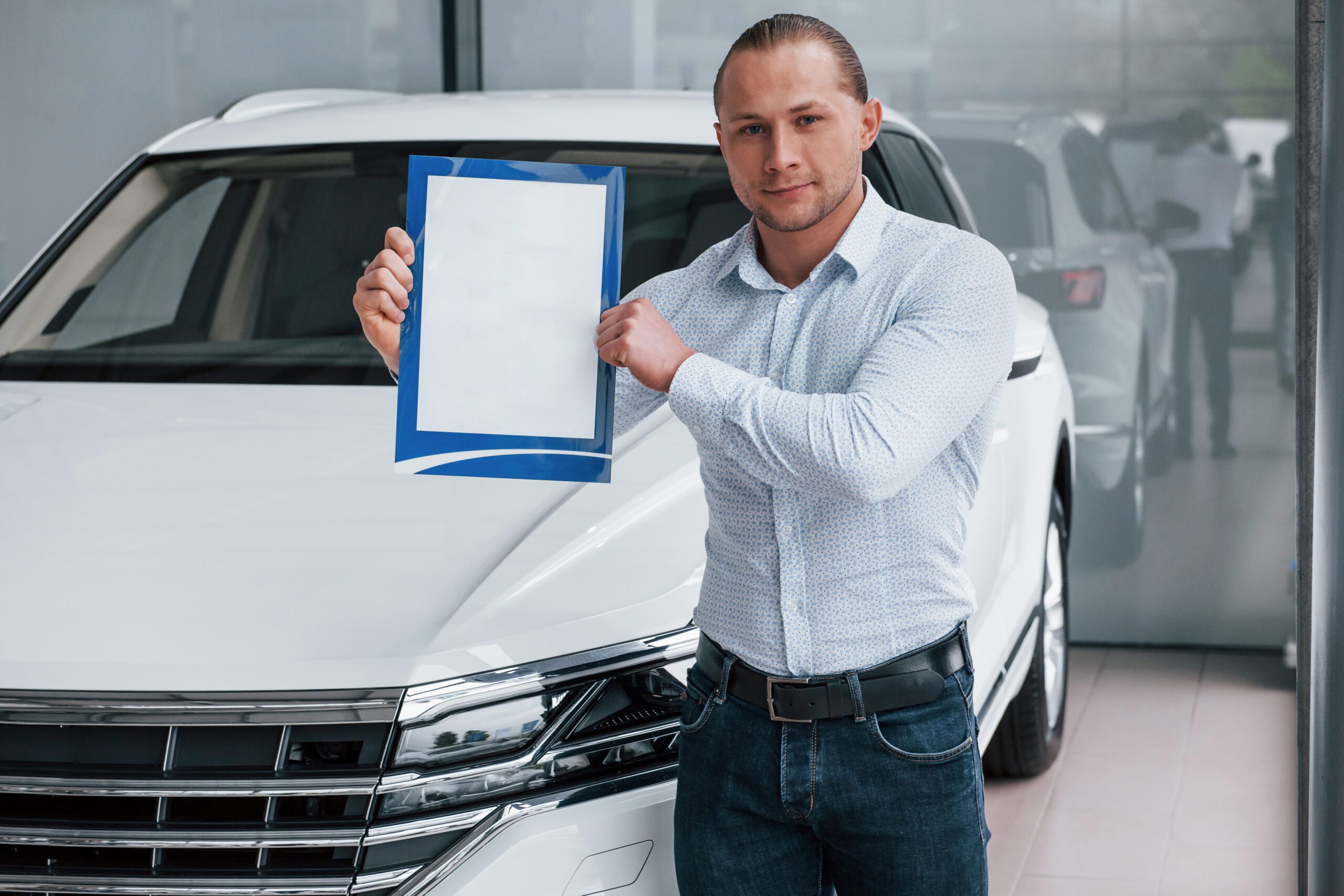 Man standing by car showing a car warranty document
