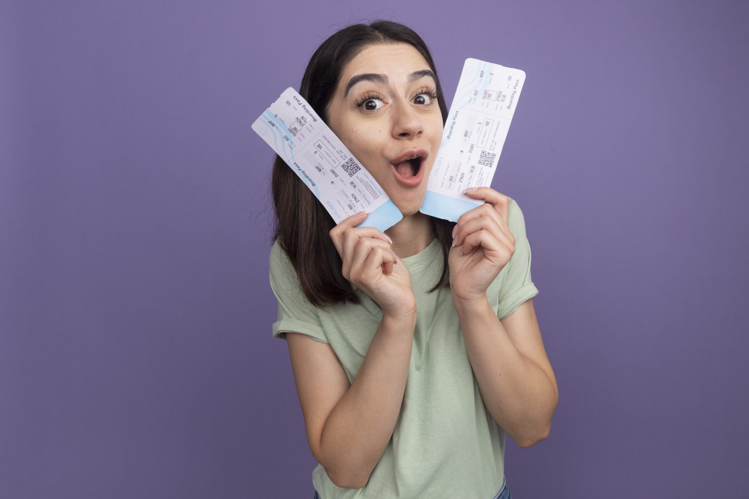 Smiling woman holding two tickets in hand